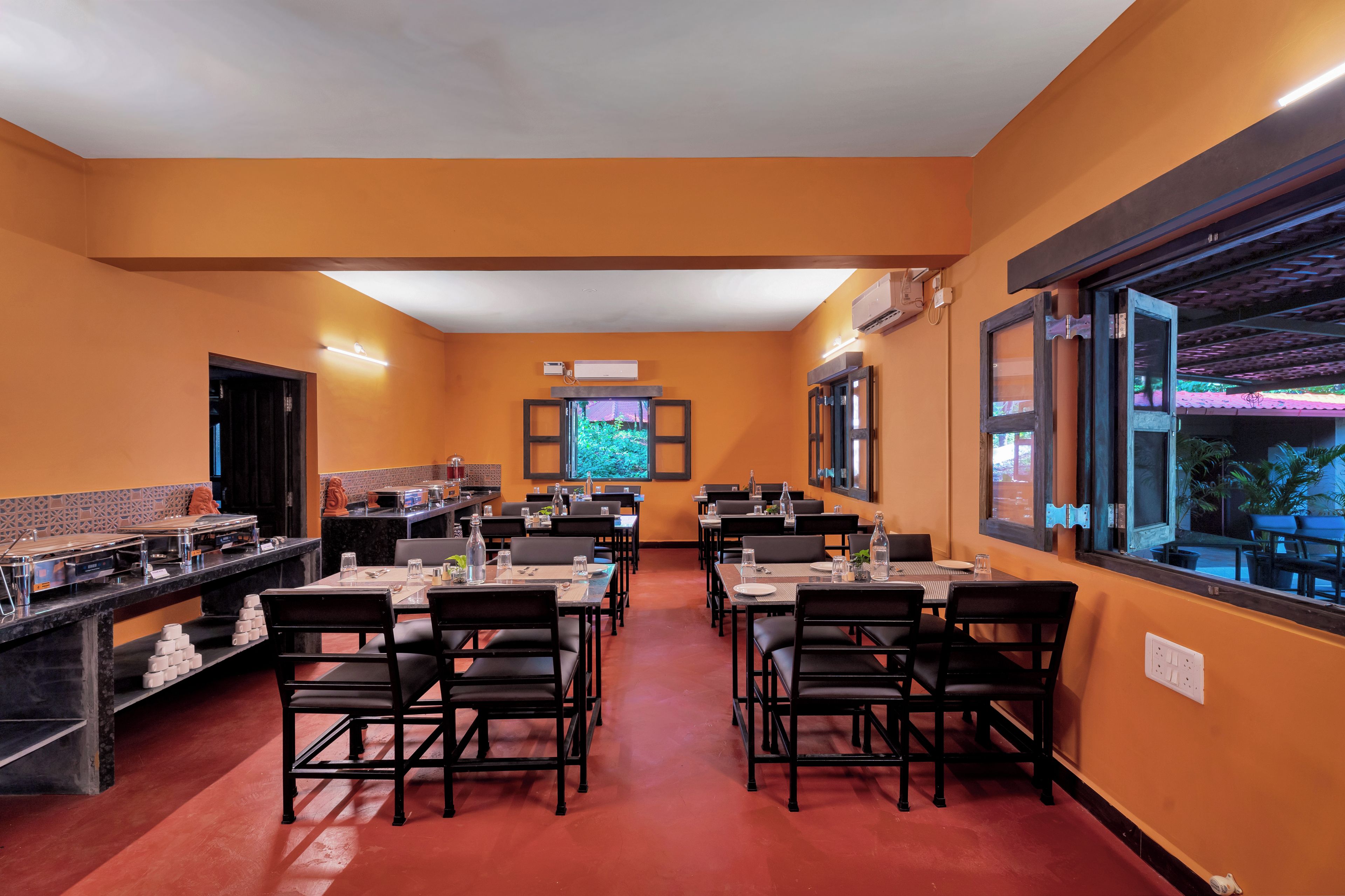 A restaurant with multiple tables and chairs, an air conditioning unit, and a large window with a view.