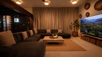 A modern living room with a sectional sofa, a coffee table, and a large flat-screen TV.