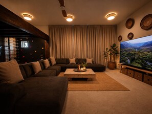 Een moderne woonkamer met een modulaire bank, een salontafel en een grote flatscreen televisie.
