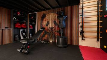 A home gym with a bench press, a punching bag, and a wall-mounted pull-up bar.
