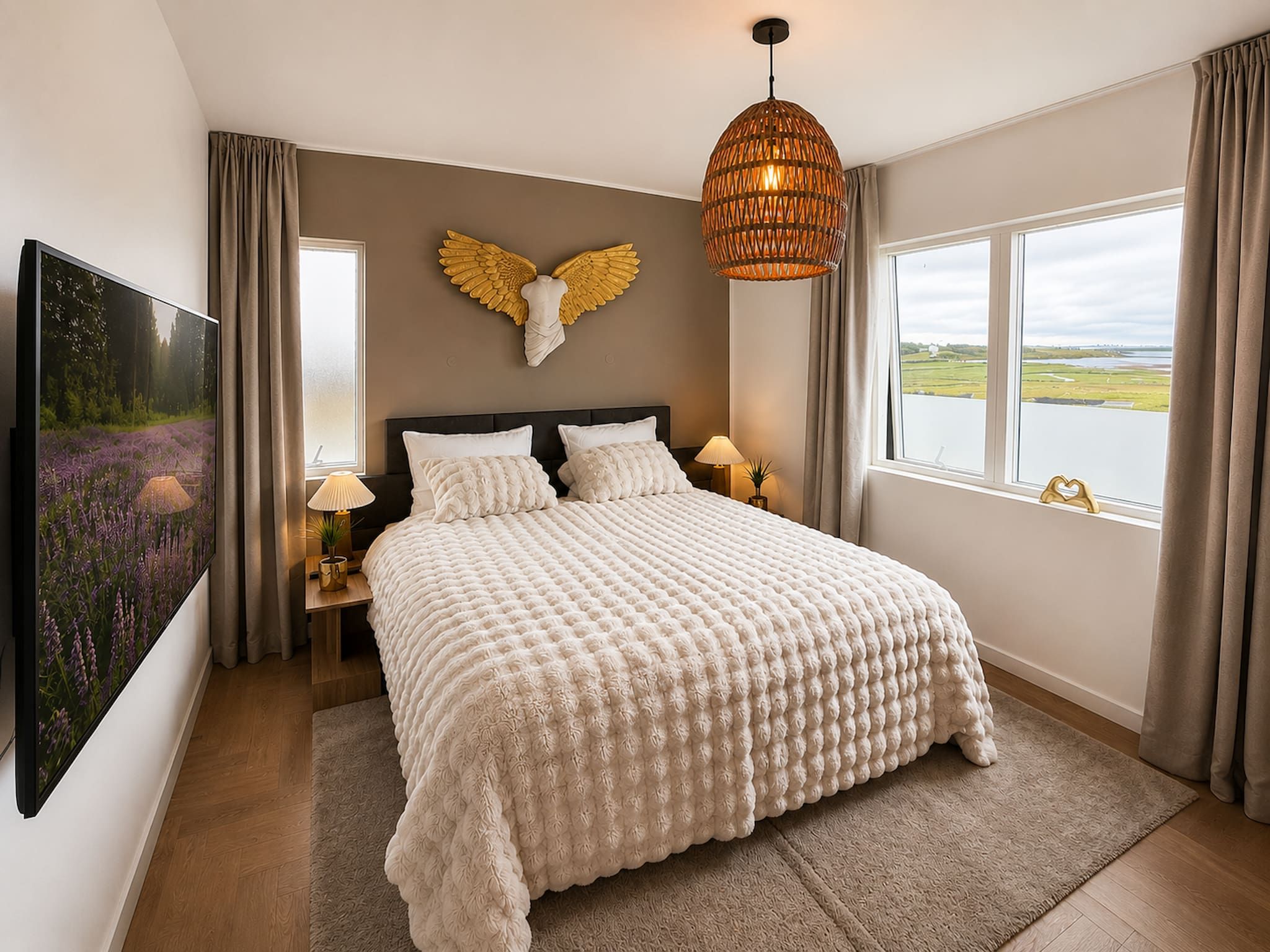 A bedroom with a large bed, a wall-mounted TV, a window with a view, and a decorative angel headboard.