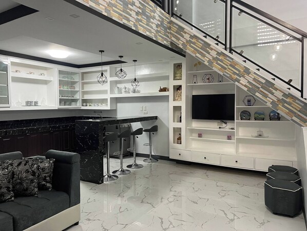 A modern kitchen with a marble countertop, white cabinetry, and a built-in TV.