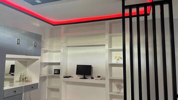 Un dormitorio moderno con televisor empotrado, estanterías y espejo.