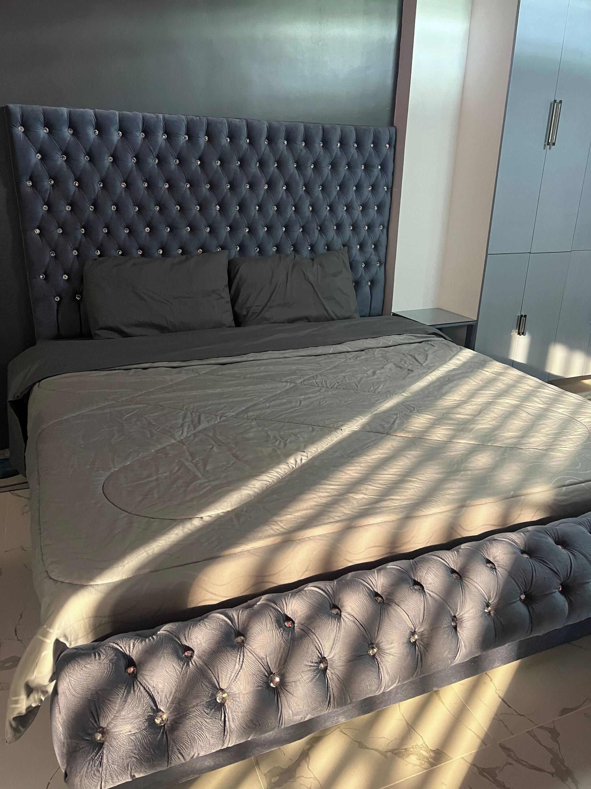 Un dormitorio con una cama grande, un cabecero con detalles capitonados y un armario.