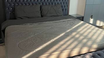 Un dormitorio con una cama grande, un cabecero con detalles capitonados y un armario.