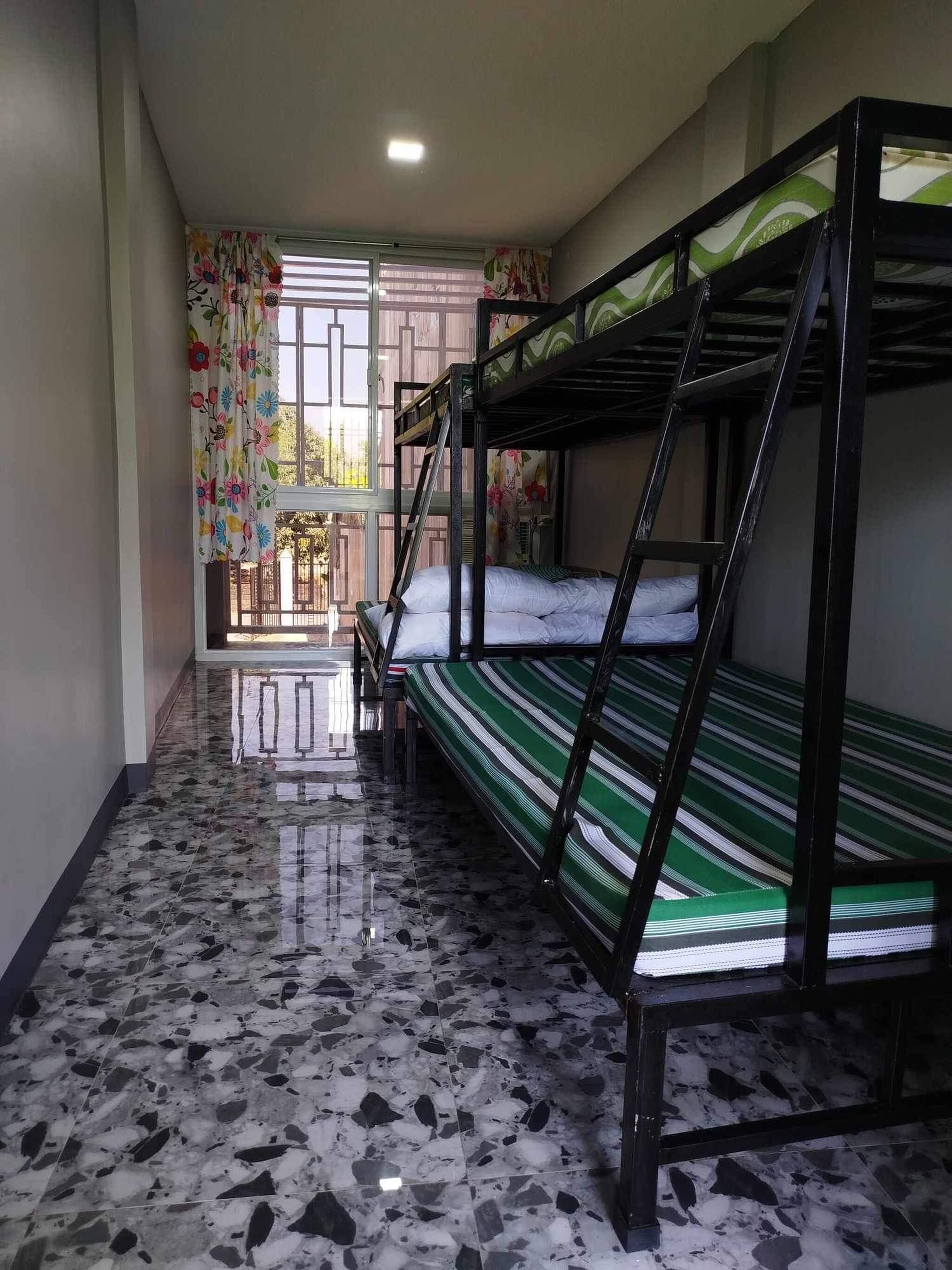 A room with bunk beds, a tiled floor, and a window with floral curtains.
