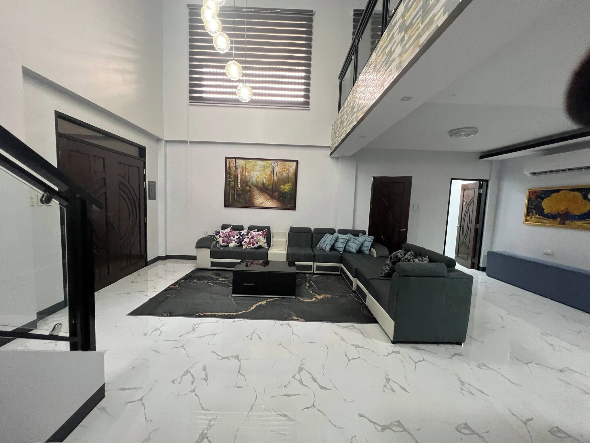 A spacious living area with a sectional sofa, a coffee table, and a large painting on the wall.