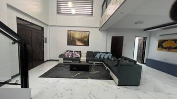 A spacious living area with a sectional sofa, a coffee table, and a large painting on the wall.