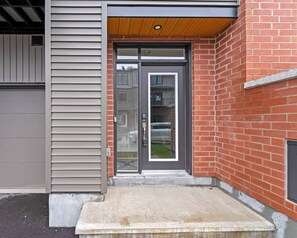 A modern two-story building with a grey siding exterior and a red brick facade. - Luxury New Home in Findlay Creek (Ottawa)