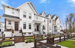 A row of white two-story houses with a wooden fence in front. - Foxfern Rowhome 4 Bed 3 Bath (Chilliwack)