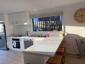 Eine moderne Küche mit weißen Schränken, einer Edelstahl-Spüle und einem großen Fenster.