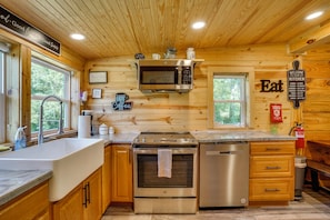 A wooden cabin kitchen with a stainless steel stove, oven, and microwave. - Hot Tub, Bar & Fire Pit! Bowdon Farm Cabin (Bowdon)