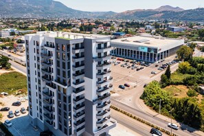A multi-story building with a parking lot in front. - One Bedroom Apartment with City View (Bar)