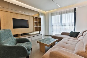 Ein modernes Wohnzimmer mit Flachbildfernseher, einer Couch, einem Couchtisch und einem TV-Schrank.