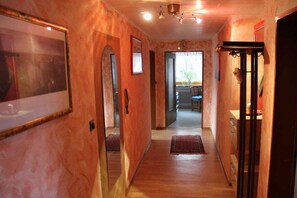 A narrow hallway with wooden flooring, a mirror on the left, and a door at the end. - Holiday apartment with 1 bedroom (Gössweinstein)