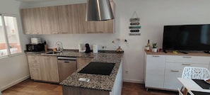 Et moderne køkken med granitbordplader, rustfrie stålapparater og træskabe.