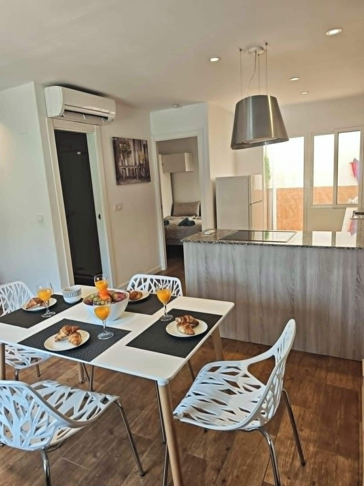 A dining area with a table set for breakfast, a kitchen area with a modern stove, and a large window providing natural light.