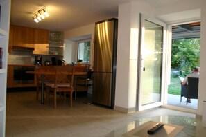 Une cuisine moderne avec des meubles en bois, un réfrigérateur en acier inoxydable et un coin repas avec des chaises.