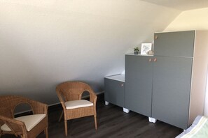 A room with a grey wardrobe, two wicker chairs, and a small table. - Friesenhaus RoseCottage in Greetsiel (Krummhörn Greetsiel)