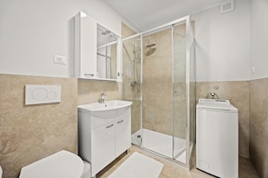 Ein modernes Badezimmer mit einer gläsernen Dusche, einem weißen Waschbecken und einer Toilette.