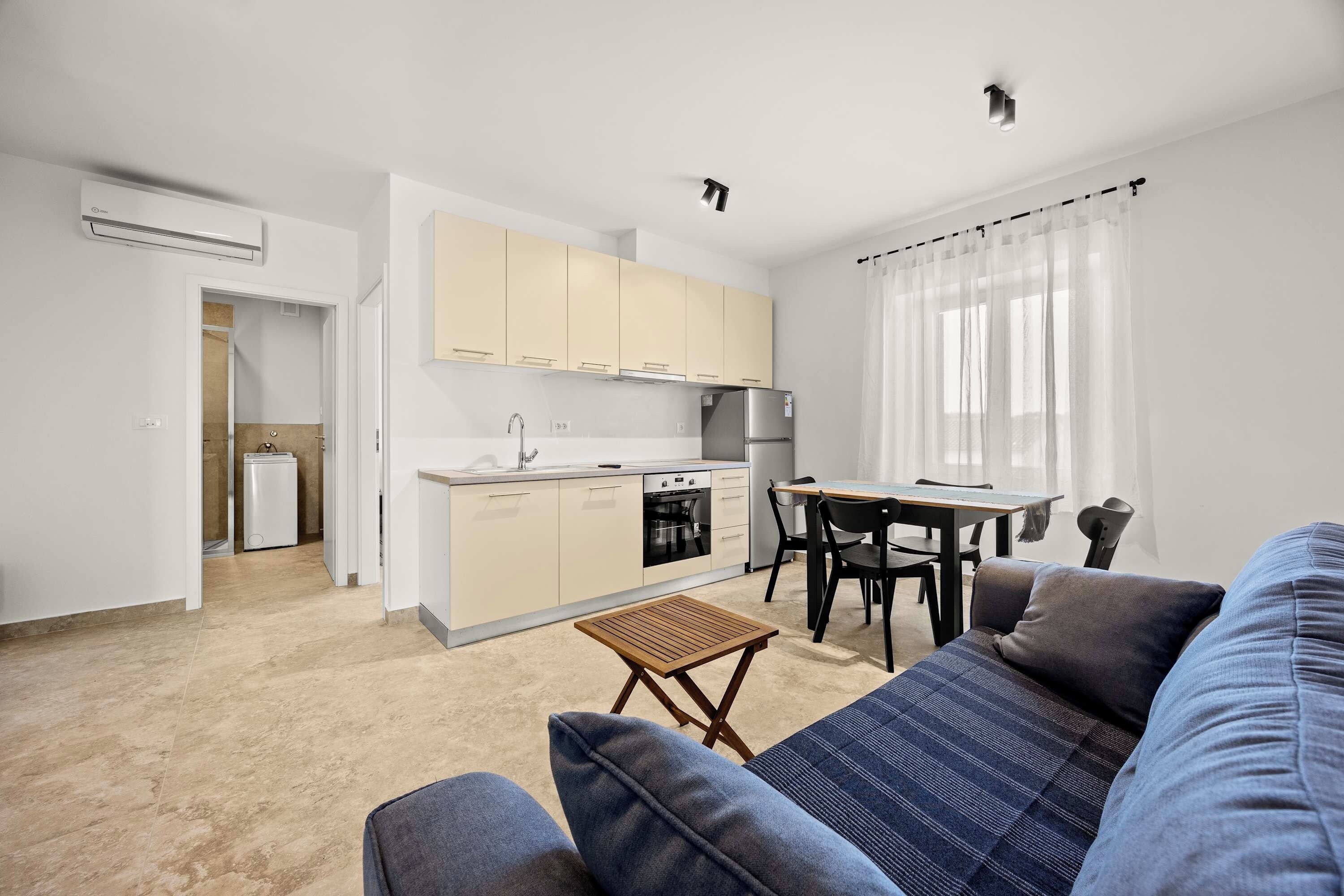 A compact living space with a kitchenette, a dining area, and a seating area with a sofa and a small table.
