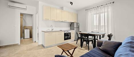 A compact living space with a kitchenette, a dining area, and a seating area with a sofa and a small table.