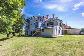 Ein mehrstöckiges Wohngebäude mit Balkon, einer Treppe und einem Garten.
