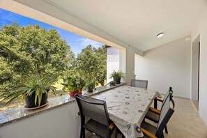 Ein Essbereich mit Tisch und Stühlen, Zimmerpflanzen und Blick auf Bäume.