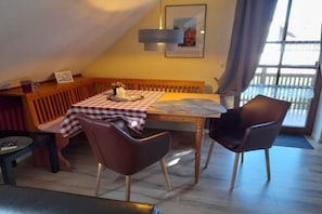 Een eetgedeelte met een geruit tafelkleed, twee stoelen, een bank en een houten tafel.