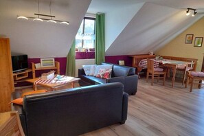Een knus loft-appartement met een eethoek, een zithoek en een televisie.