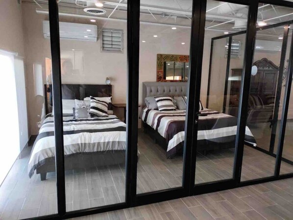 A hotel room with two beds, a large mirror, and a sliding glass door.