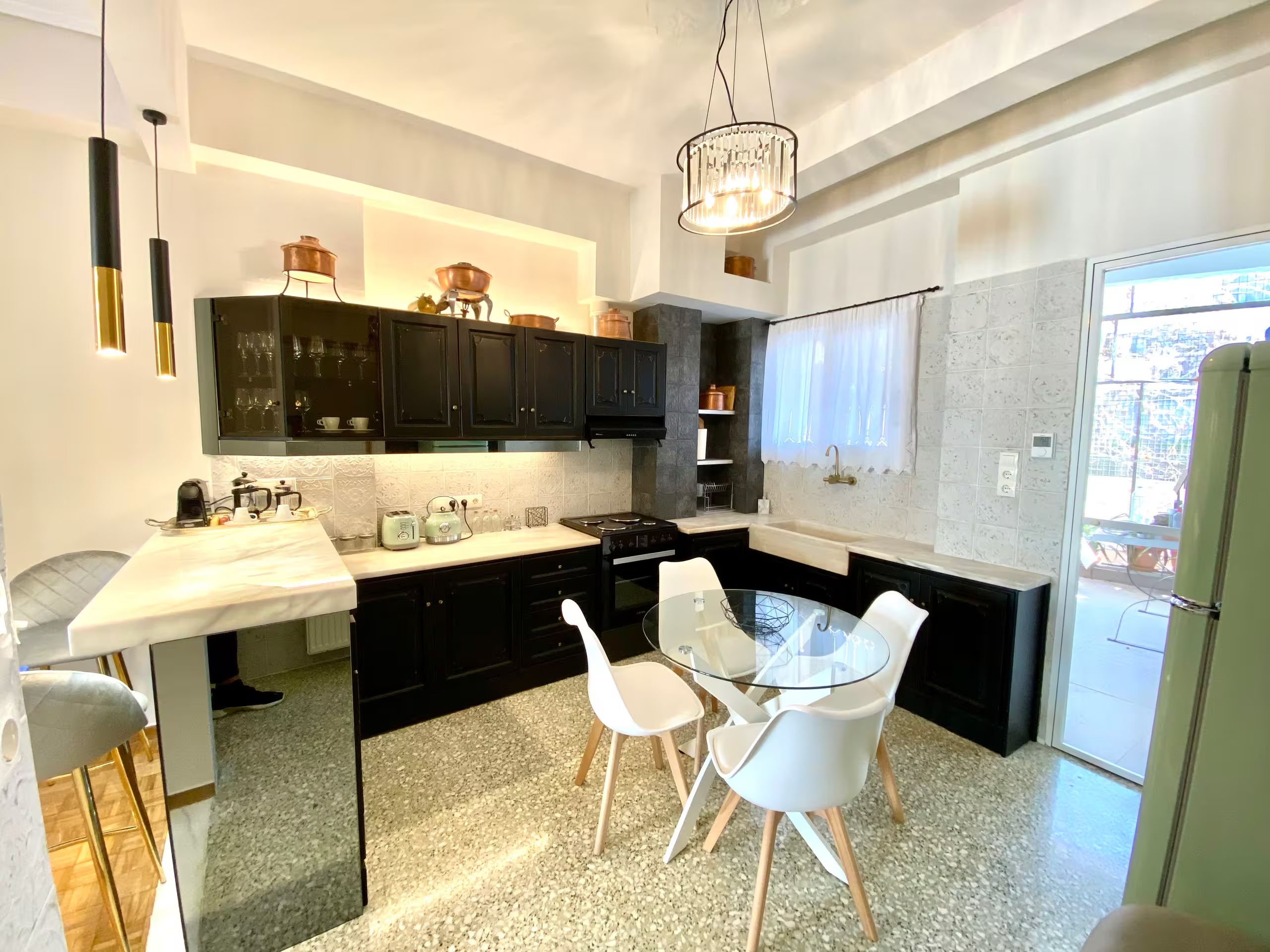 A modern kitchen with black cabinets, a white countertop, and a glass dining table with white chairs.