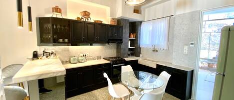A modern kitchen with black cabinets, a white countertop, and a glass dining table with white chairs.