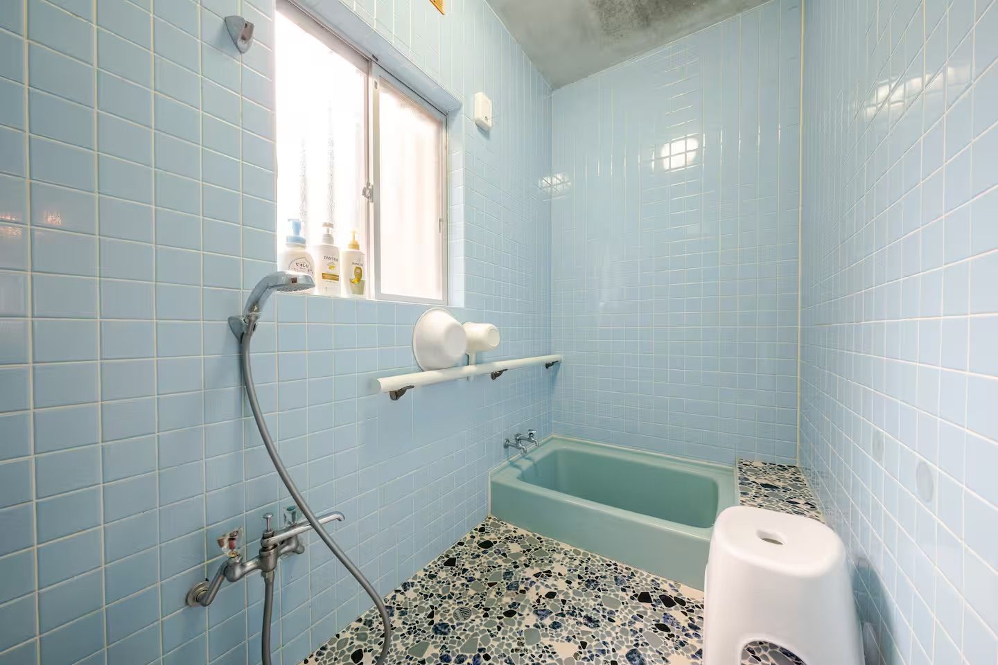 A bathroom with a bathtub, a window, and a shower.