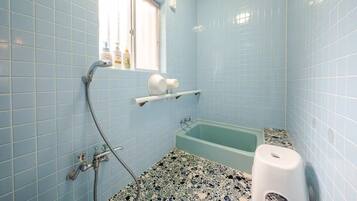 A bathroom with a bathtub, a window, and a shower.