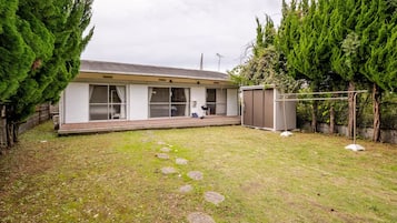 A residential property with a house, a covered patio, a fenced yard, and a small shed.