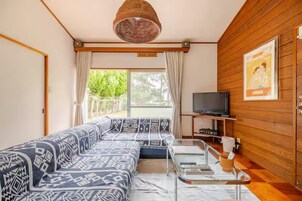 Una sala de estar con un sofá estampado, un televisor y una pared de madera.