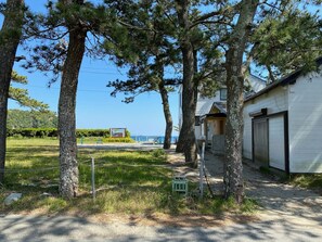 A residential area with a white garage, a paved driveway, and a grassy yard with trees. - KIKA STAY (Minamiizu)