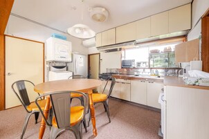Una cocina funcional con una mesa, sillas, refrigerador, estufa y microondas.