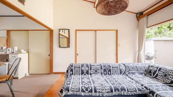 A bedroom with a bed, a desk, a chair, a mirror, and a hanging light fixture.