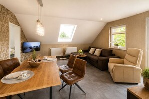 Een moderne woonkamer met een eettafel, leren stoelen, een bank en een fauteuil.