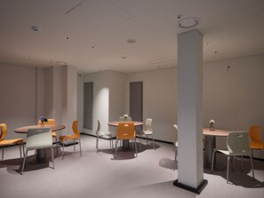 A modern conference room with round tables and chairs, a large pillar, and recessed ceiling lights. - Travelodge Gangnam Yeoksam Seoul (Seoul)