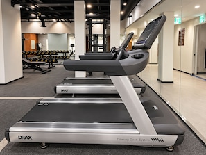 A gym with treadmills, weight machines, and dumbbells.