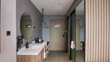A modern bathroom with a dual sink vanity, a large mirror, and a walk-in shower.