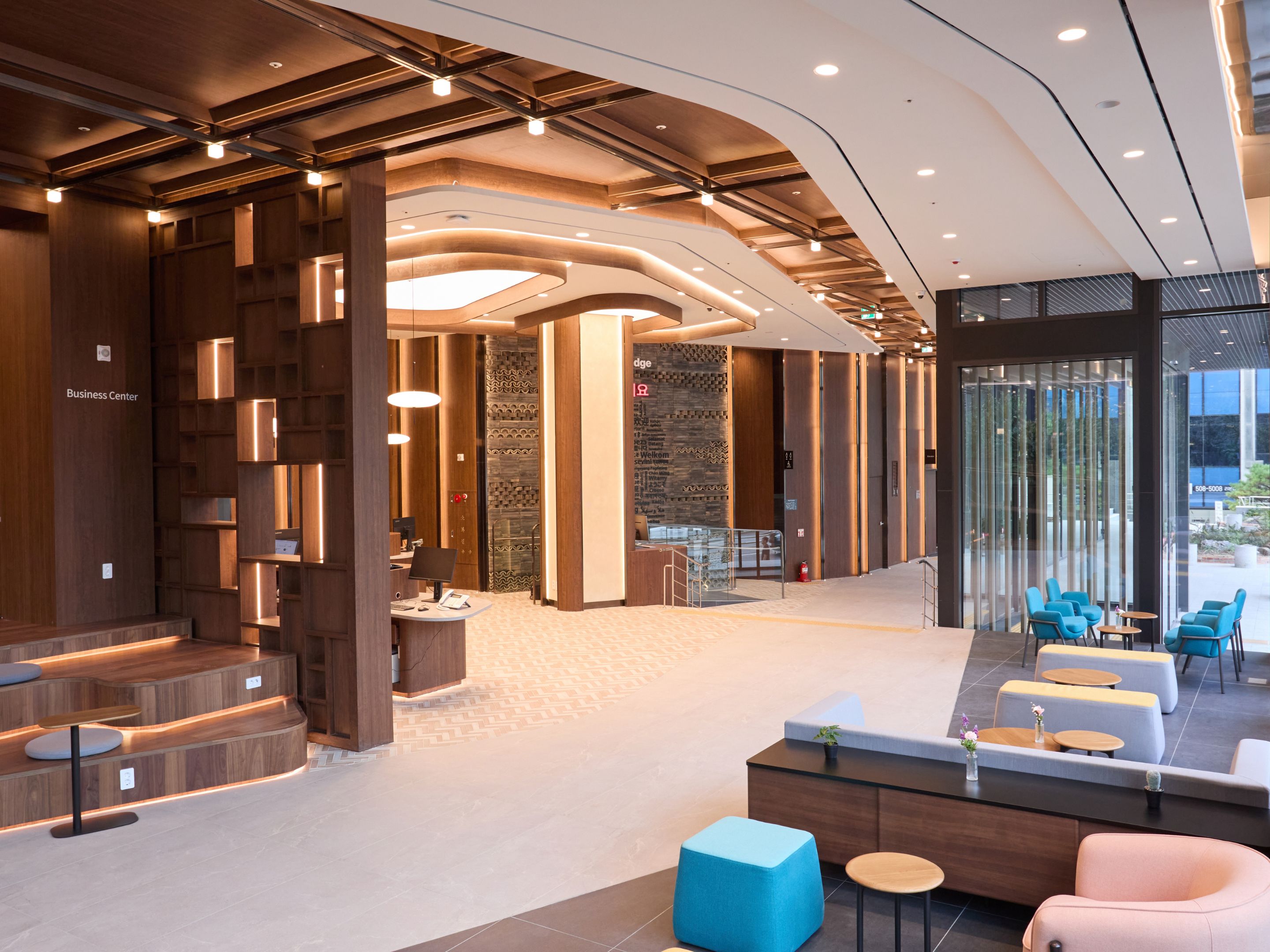 A modern lobby with a reception desk, seating area, and a staircase.