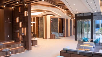 A modern lobby with a reception desk, seating area, and a staircase.