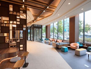 A modern interior with a reception desk, seating area, and large windows offering a view of the street. - Travelodge Gangnam Yeoksam Seoul (Seoul)