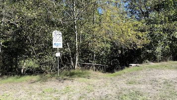 A signpost with directional information and a natural landscape with trees and a dirt path.