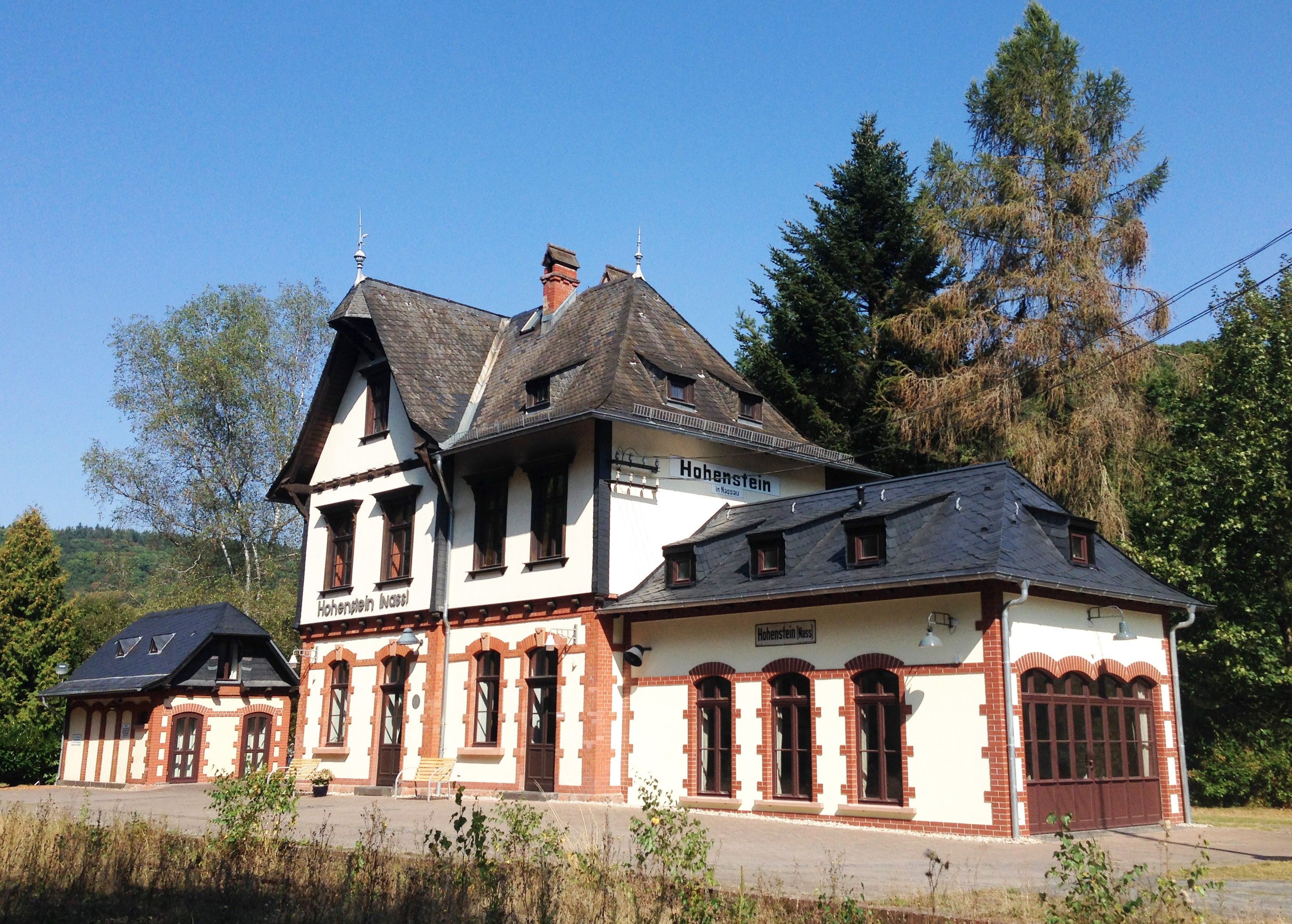 A traditional building with a steeply pitched roof, multiple windows, and a sign indicating 'Hohenstein in Nassau.'