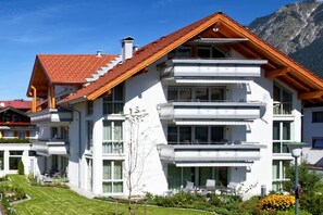 A multi-story residential building with a sloped roof, balconies, and a well-maintained lawn. - Bernstein Suite DUKE ALBRECHT (Oberstdorf)